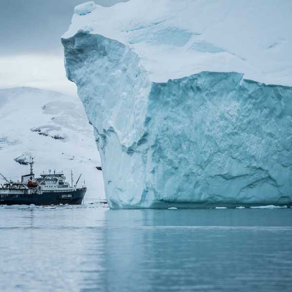 A ship sailing past a large iceberg