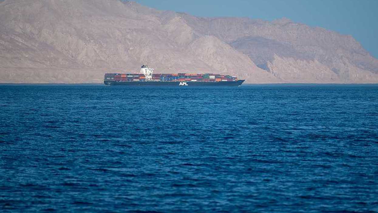 A ship sailing through the Strait of Hormuz with dry mountains in the background