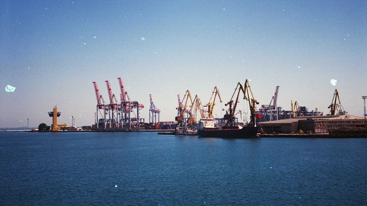 A shipping port with ships, docks and cranes on a sunny day