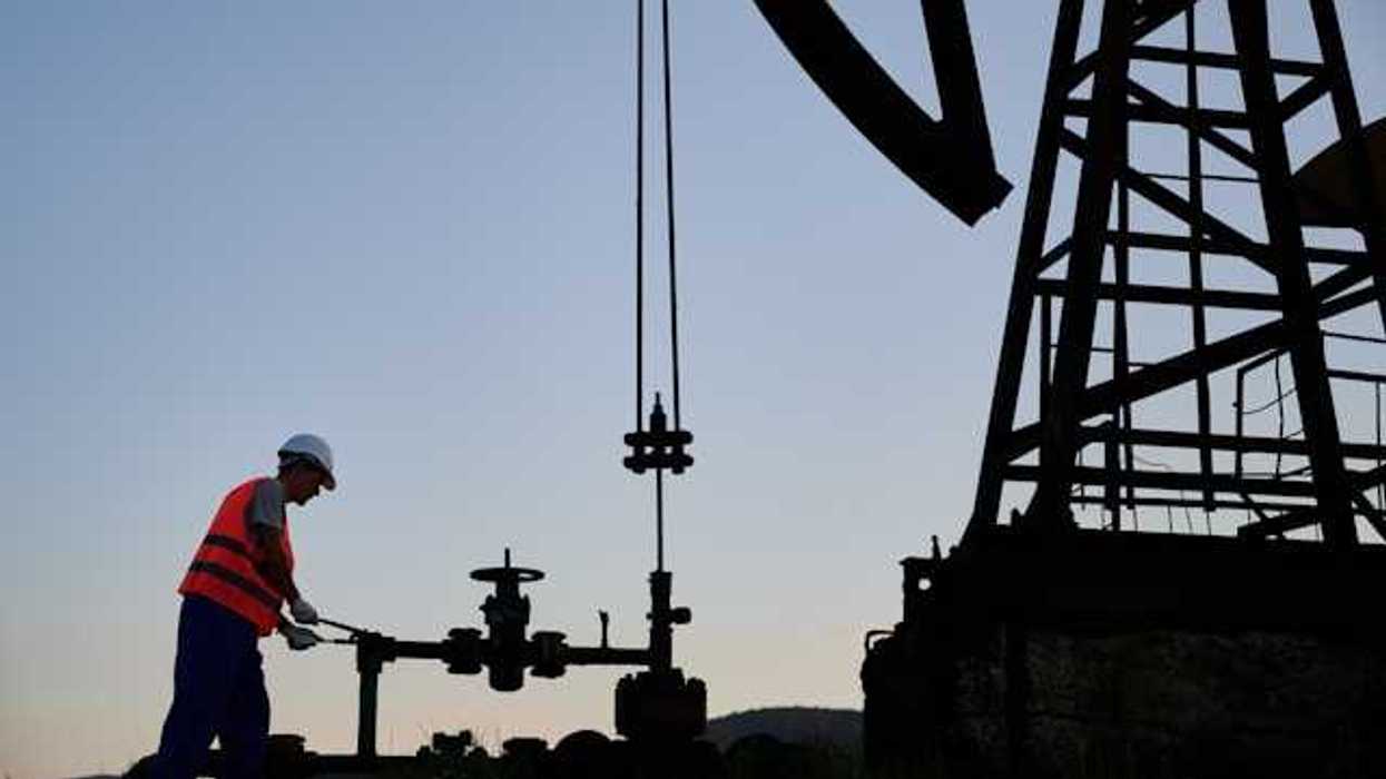 A silhouette of an energy worker next to an oil dril