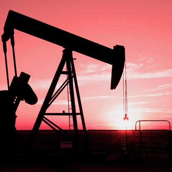 A silhouette of an oil pump jack with the sunset in the distance
