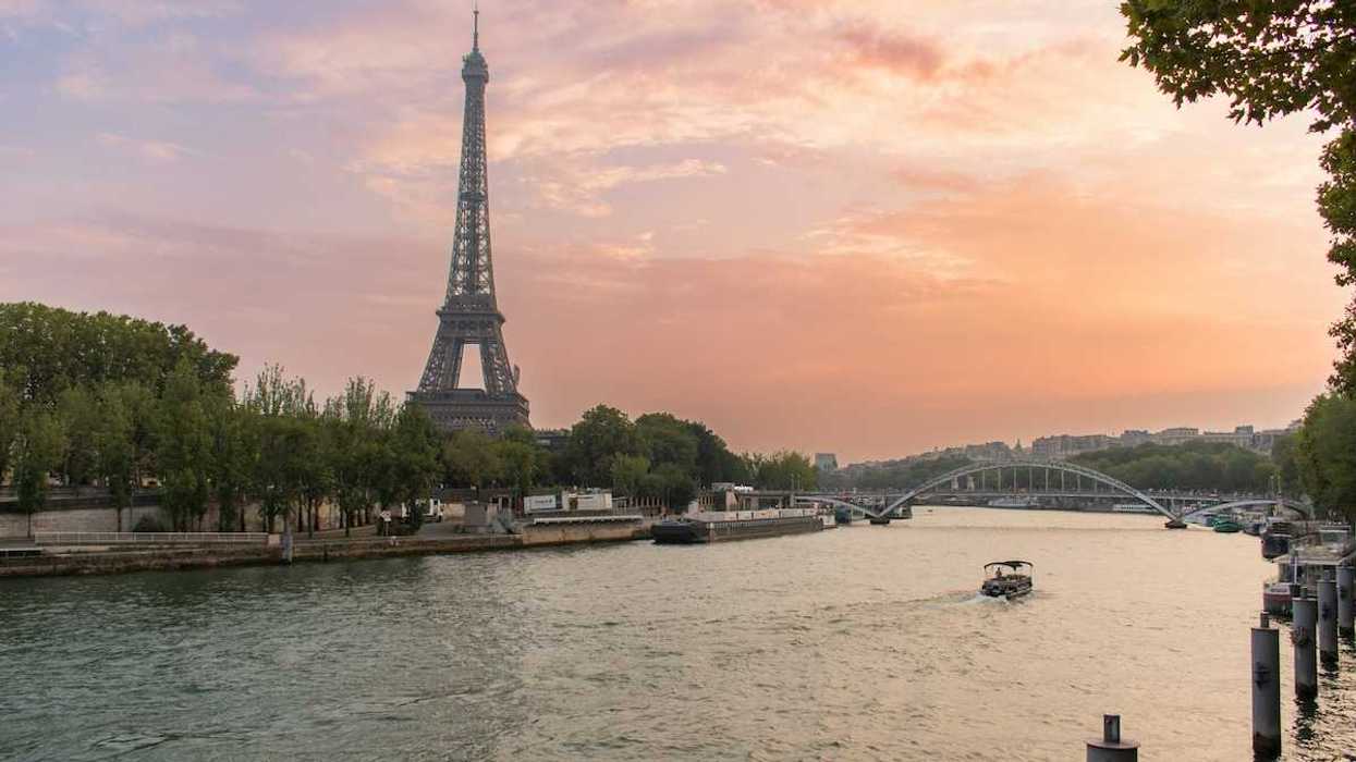A single boat traveling the river Seine with the Eiffel Tower behind