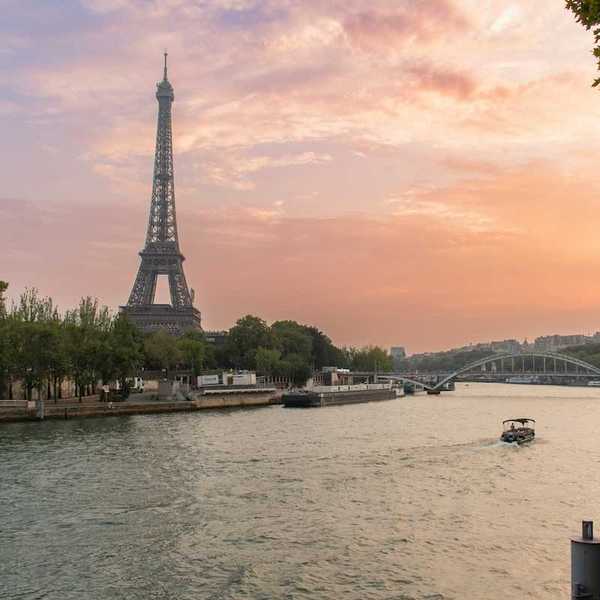 A single boat traveling the river Seine with the Eiffel Tower behind