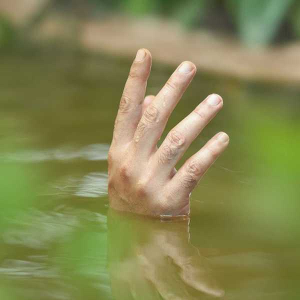 A single hand poking up out of floodwaters
