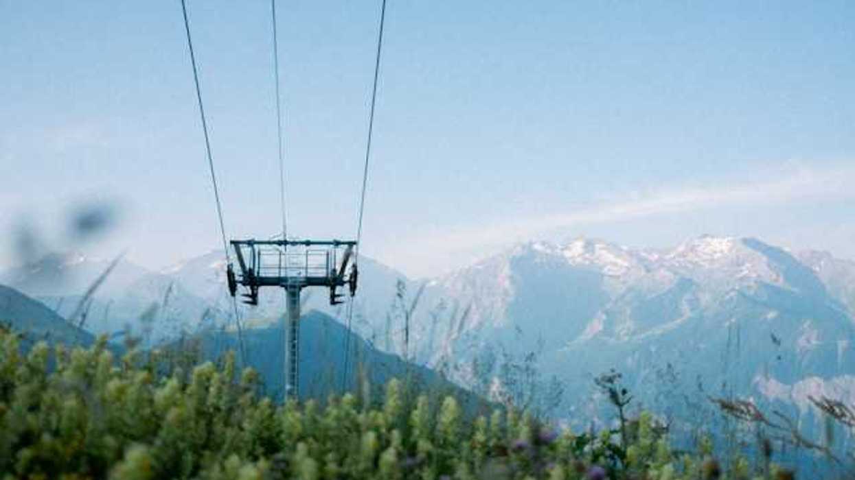 A ski run with green bushes growing under it and mountains the background