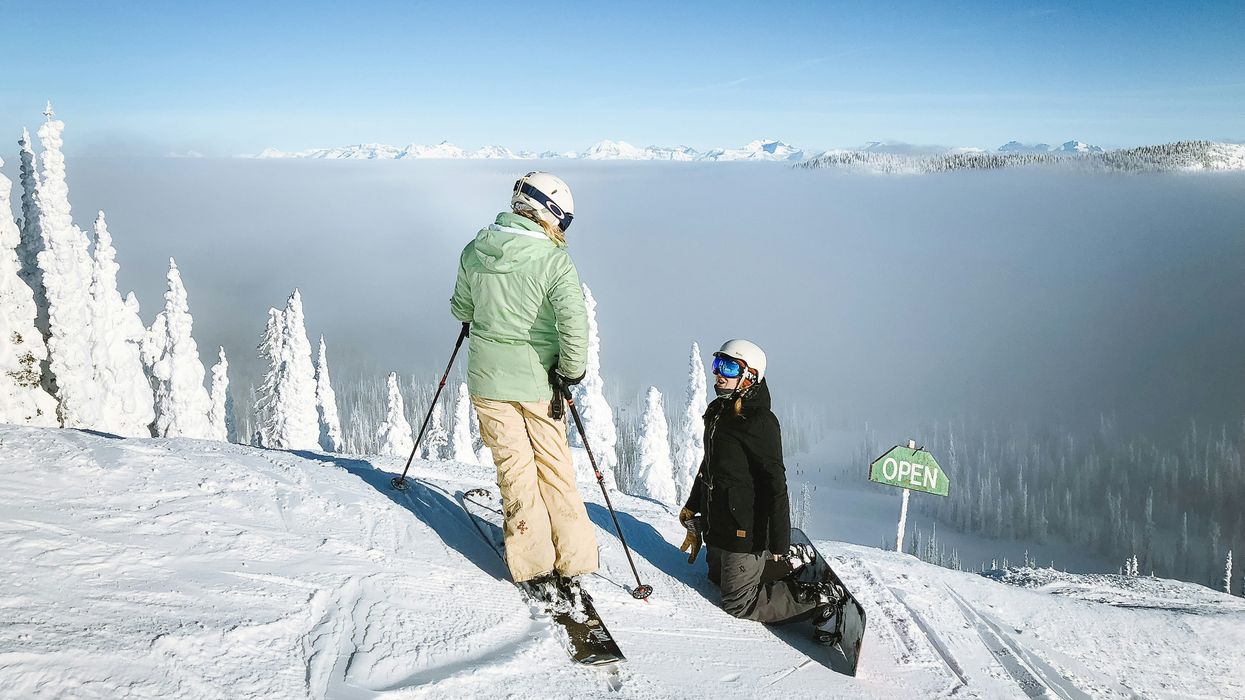 A skier and snowboarding on top of a slope