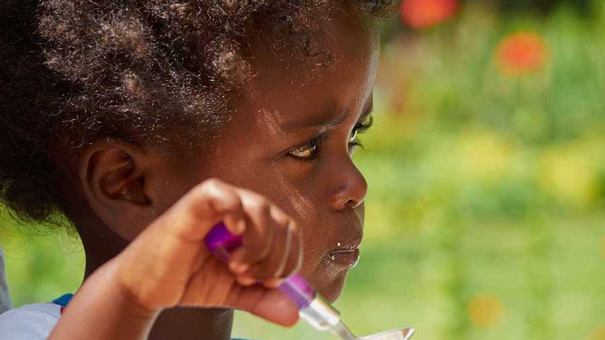 A small black child eating with a spoon