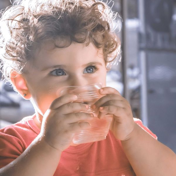 a small child drinking from a plastic glass.