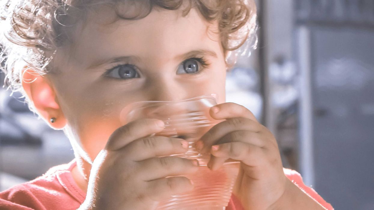 a small child drinking from a plastic glass.