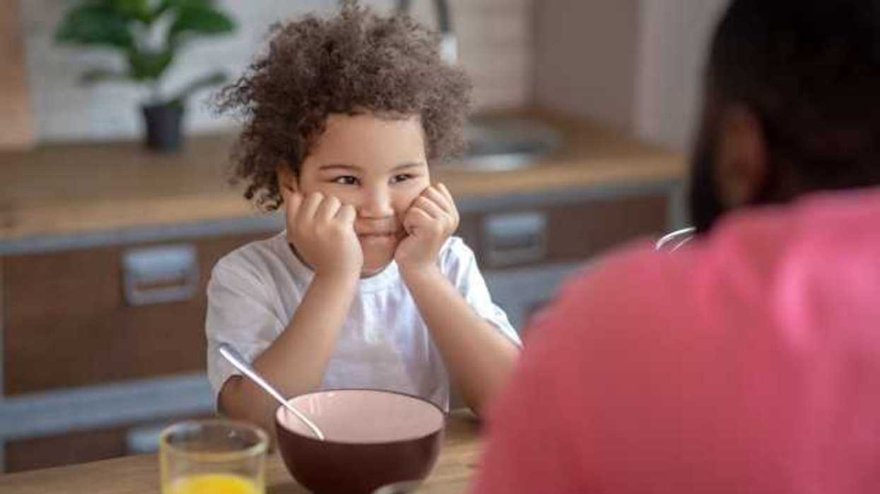 A small child sitting at a table with an empty bowl in front of him