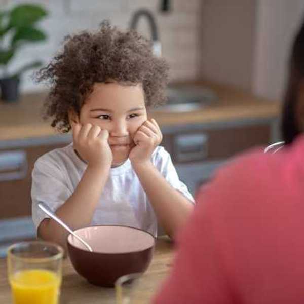 A small child sitting at a table with an empty bowl in front of him