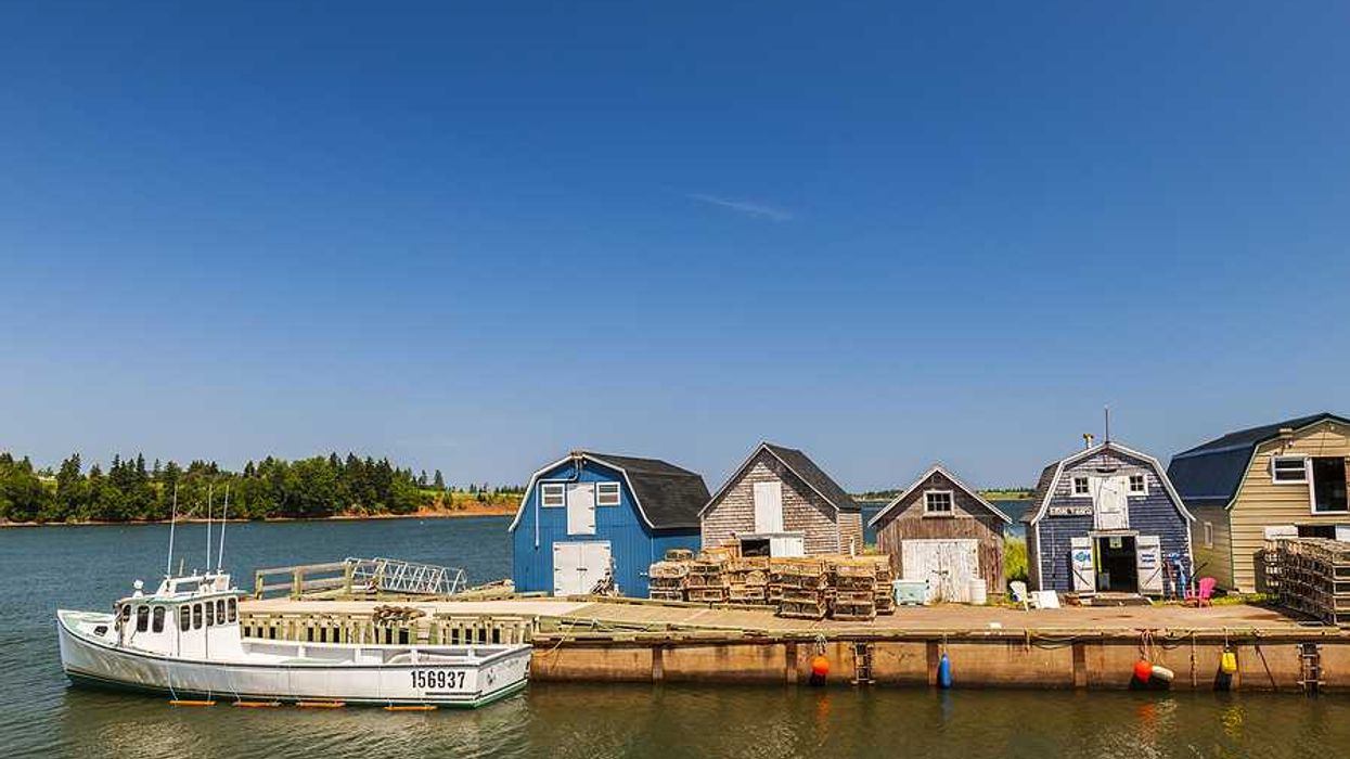A small dock with fishing shacks on the water