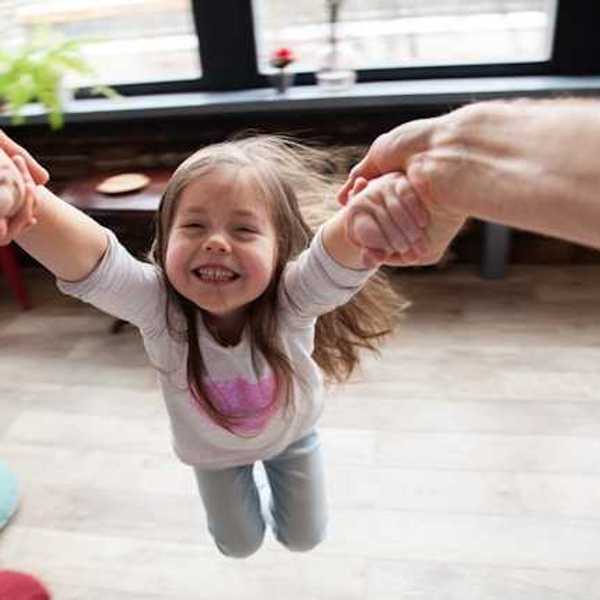 A small girl being twirled in the air by her parent