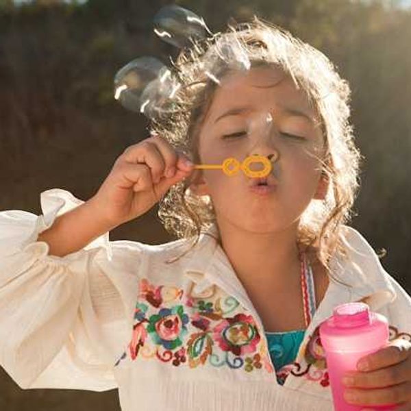 A small girl blowing bubbles from a plastic bubble maker