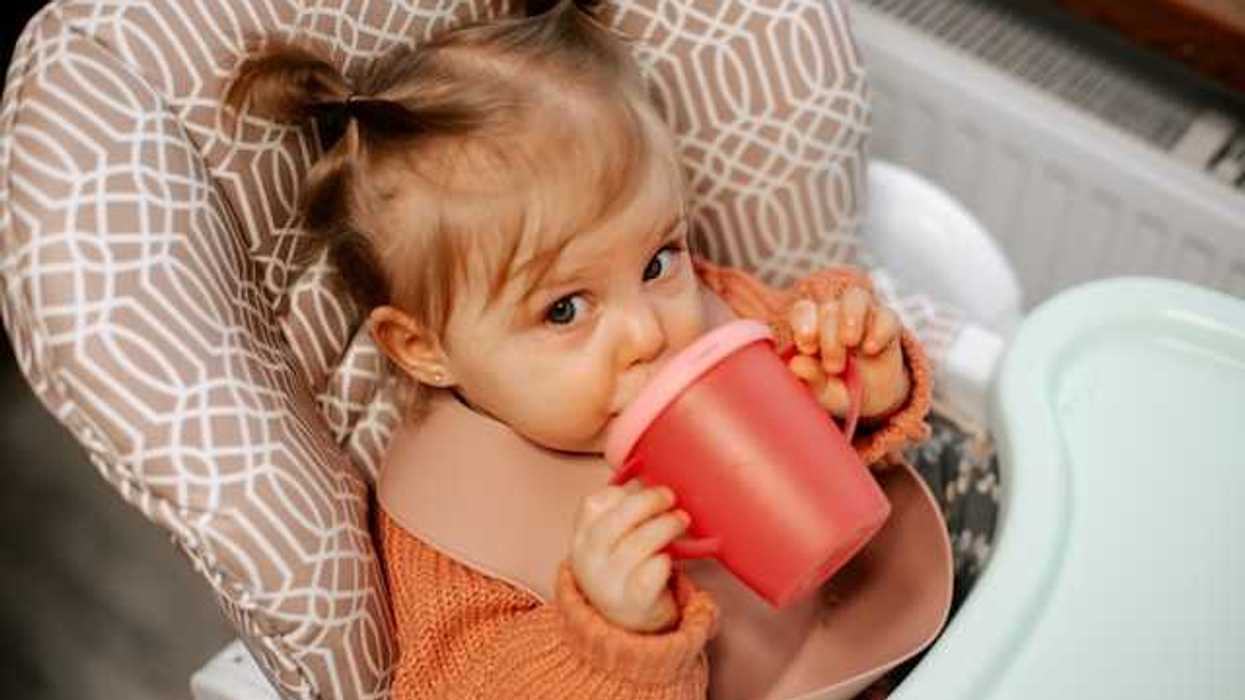 A small girl drinking from a sippy cup