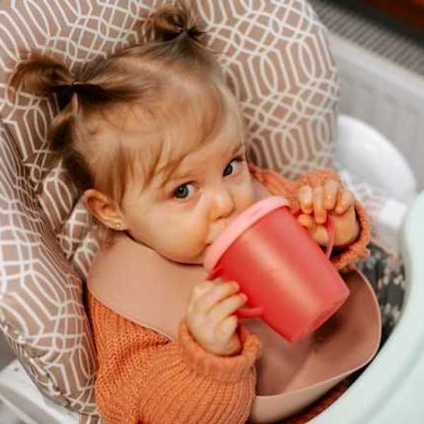 A small girl drinking from a sippy cup