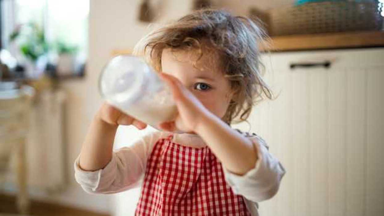A small girl drinking milk out of a bottle