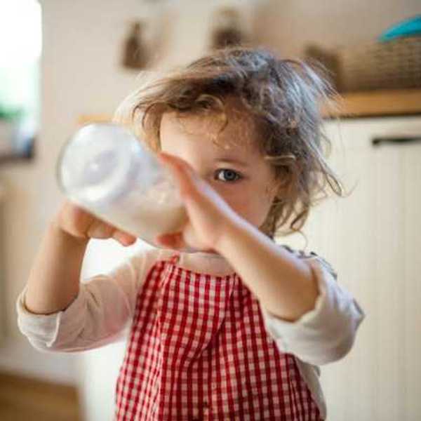 A small girl drinking milk out of a bottle