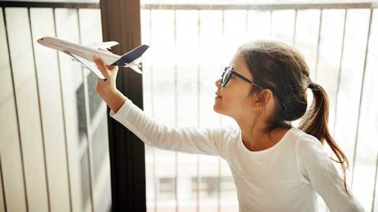 A small girl holding a model of an airplane
