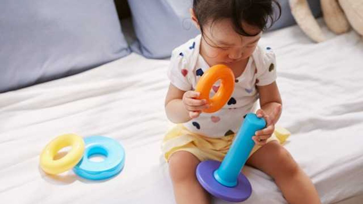 A small girl sitting on a sofa playing with a plastic toy