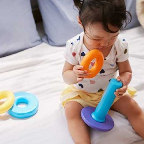 A small girl sitting on a sofa playing with a plastic toy