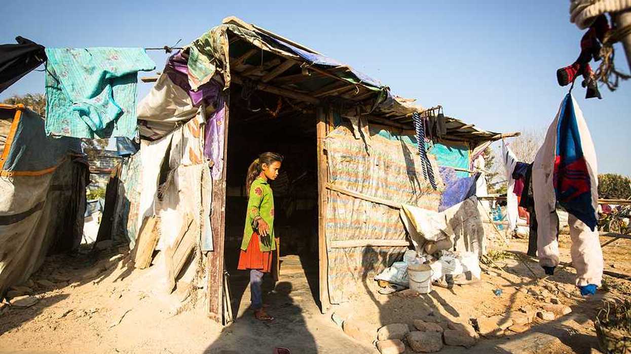 A small girl standing in the doorway of a hut