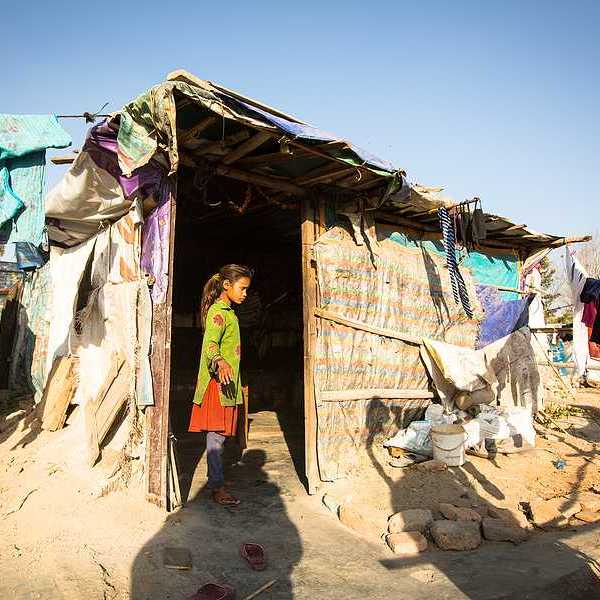 A small girl standing in the doorway of a hut