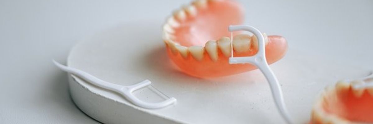 A small white platform with dentures and plastic flossers.