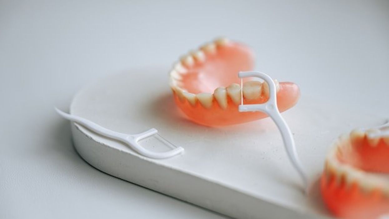 A small white platform with dentures and plastic flossers.