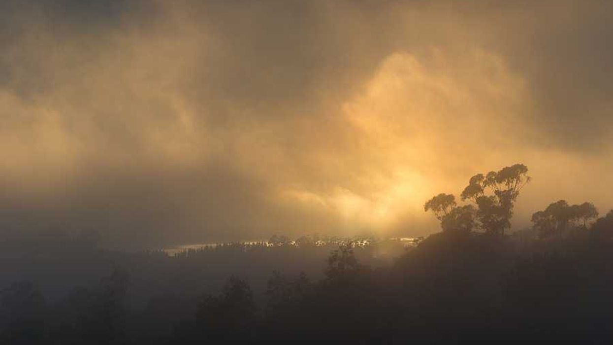 A smoky landscape with the sun in the background