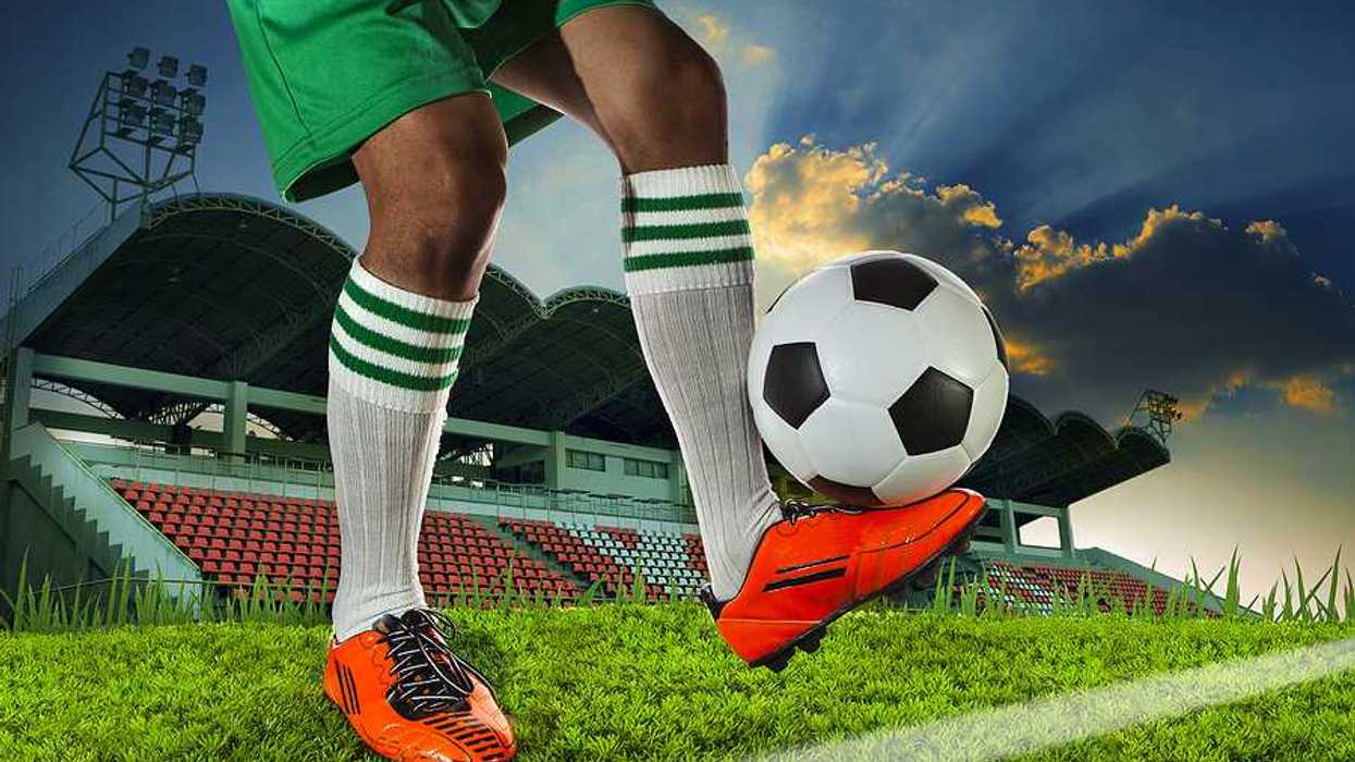 A soccer player balancing a soccer ball on the top of his foot