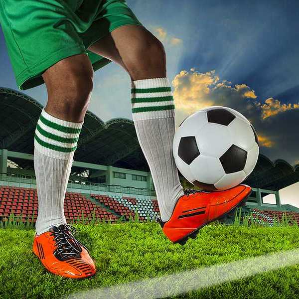 A soccer player balancing a soccer ball on the top of his foot