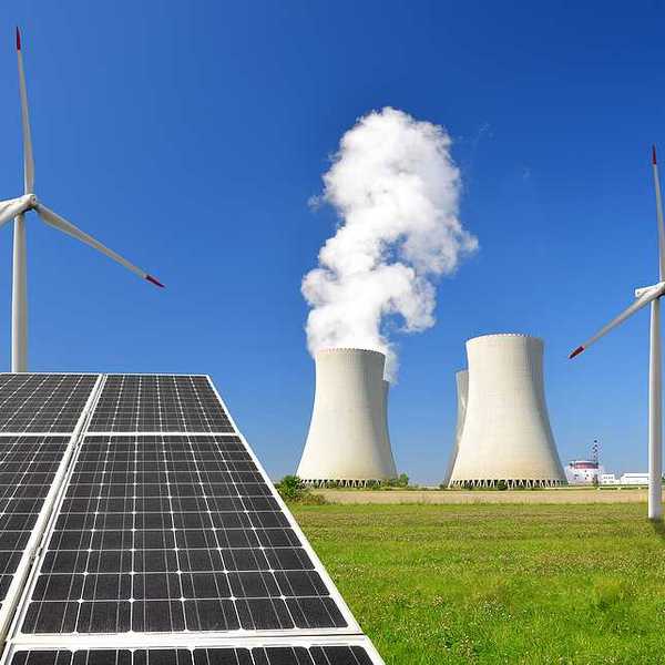 A solar panel with wind turbines and an energy plant in the background