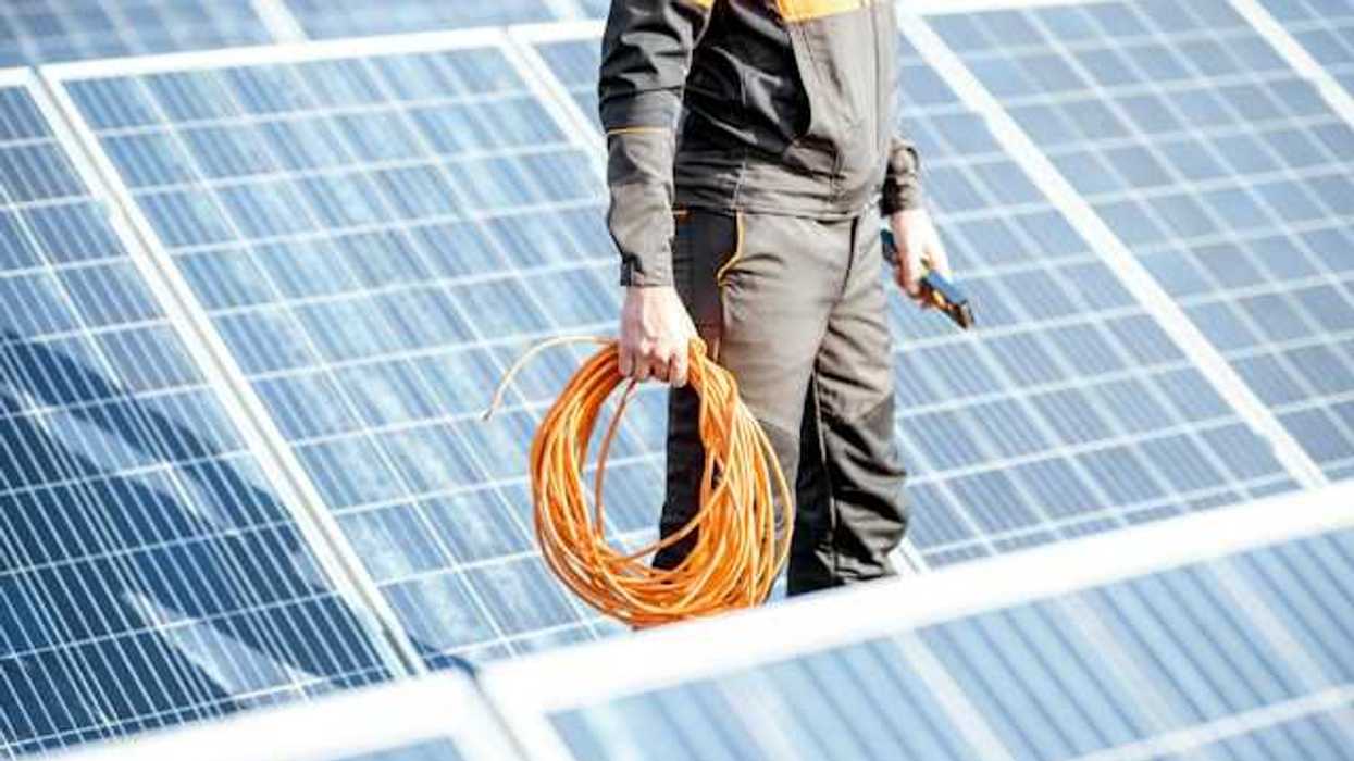 A solar power worker standing between rows of solar panels
