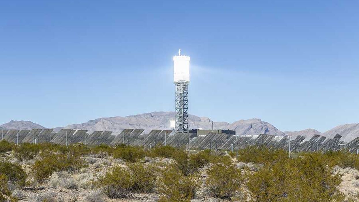A solar tower above a desert landscape with solar panels