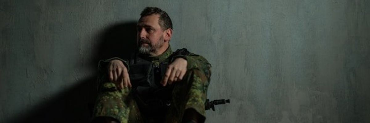 A soldier sitting on the floor leaning against a wall.