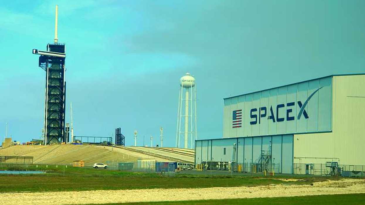 A SpaceX building with a rocket launching tower in the distance