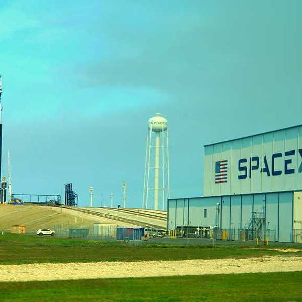 A SpaceX building with a rocket launching tower in the distance