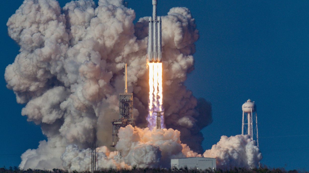 A spaceX rocket launching with billowing smoke in the background