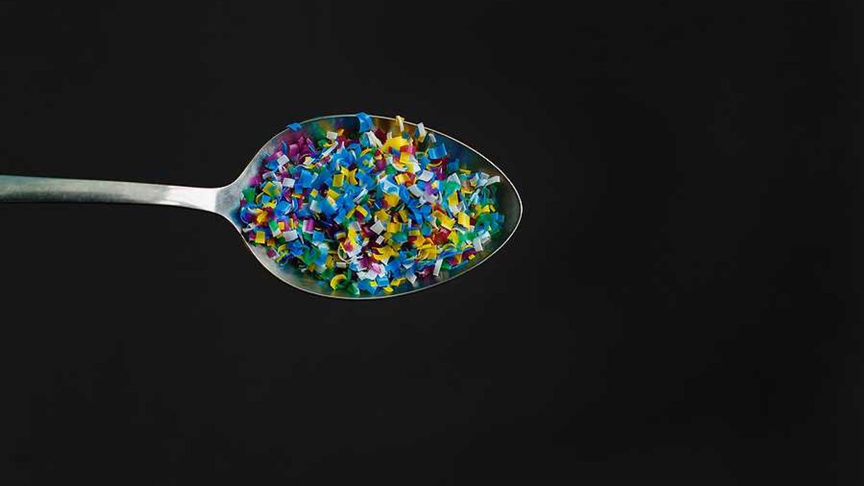 A spoon with microplastics in it on a black background