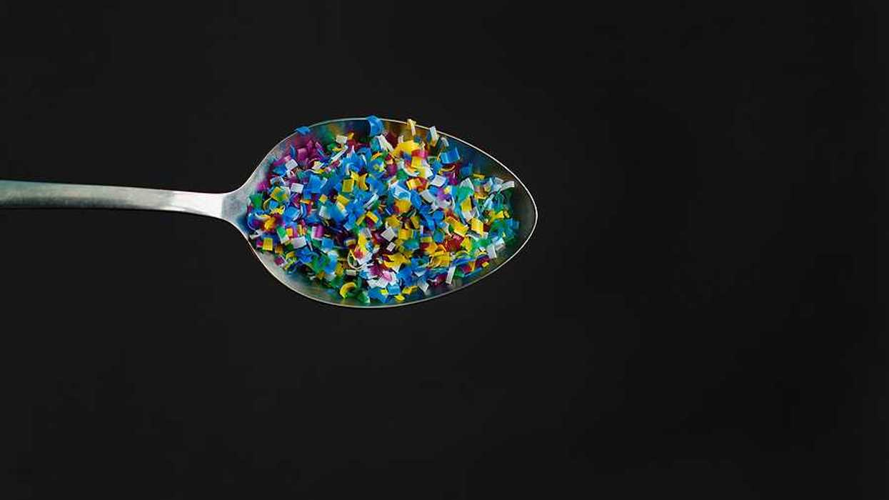 A spoon with small pieces of plastics in it against a black background