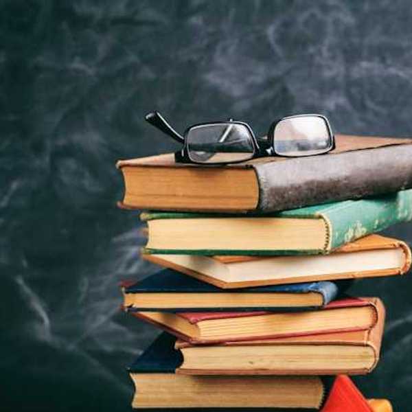 A stack of books with a pair of readers sitting atop it