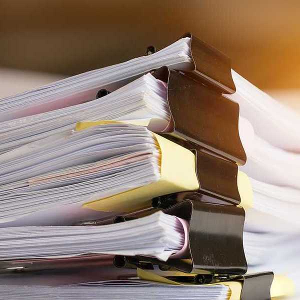 A stack of paperwork with big metal clips holding them together