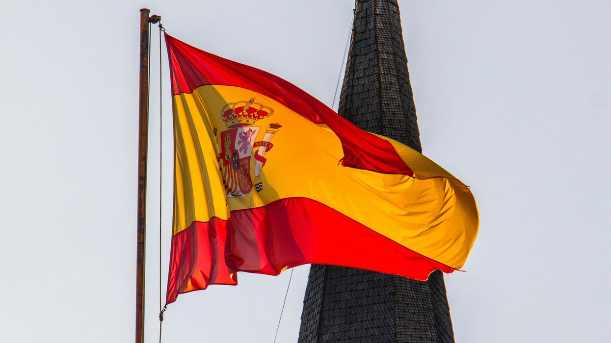 A statue with a Spanish flag on top of a building.