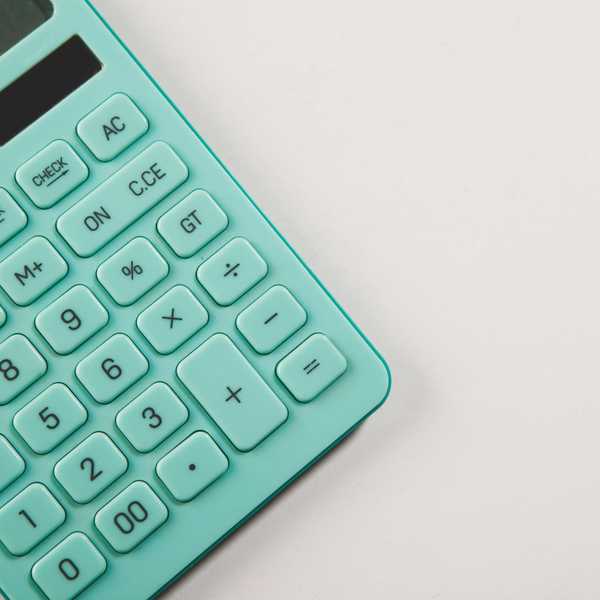 A teal calculator rests on a white surface.