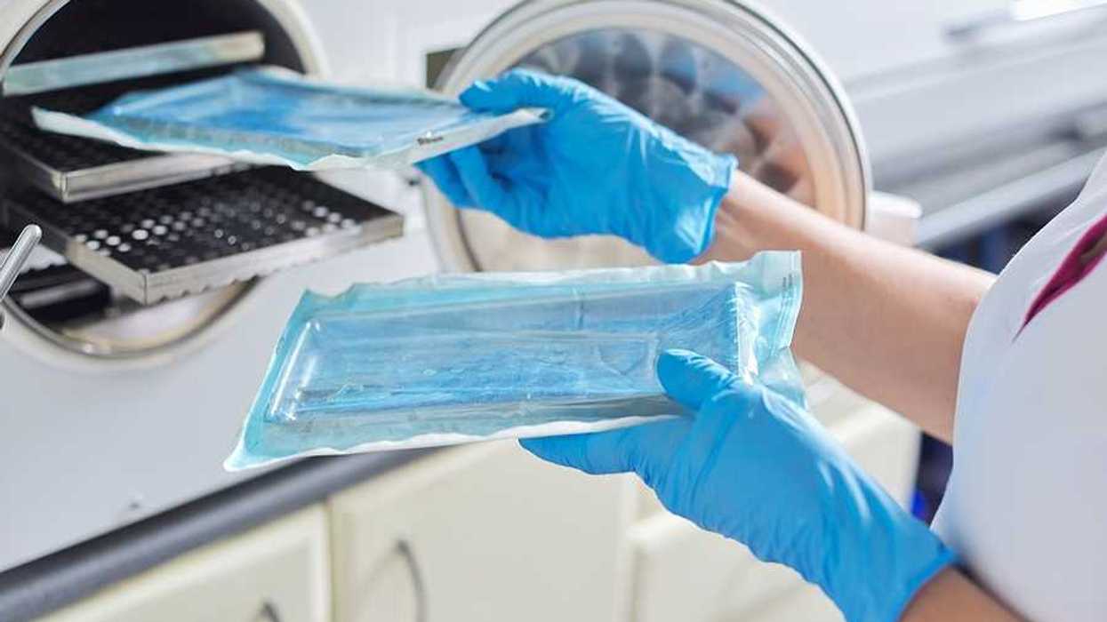 A technician putting medical instruments into a sterilization machine
