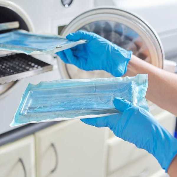 A technician putting medical instruments into a sterilization machine
