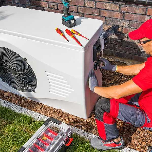A technician working on a heat pump outside a house