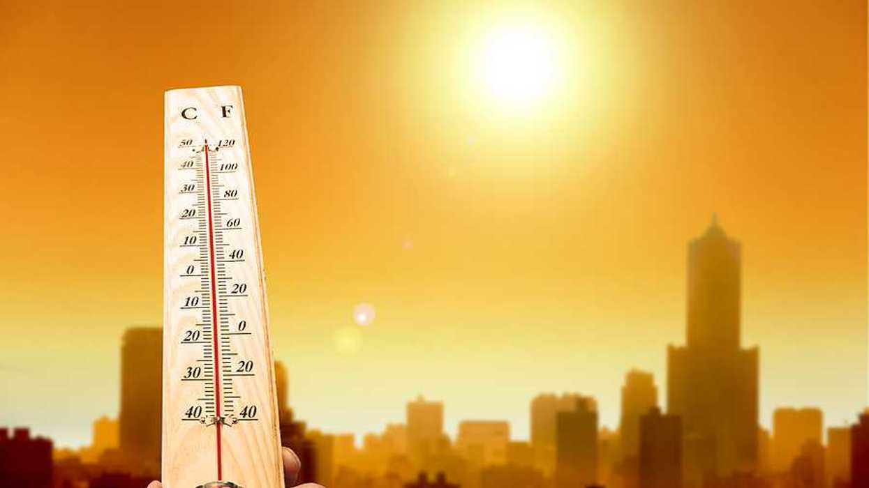 A thermometer showing hot temperatures with the outline of a city in the background