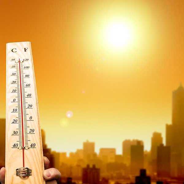 A thermometer showing hot temperatures with the outline of a city in the background